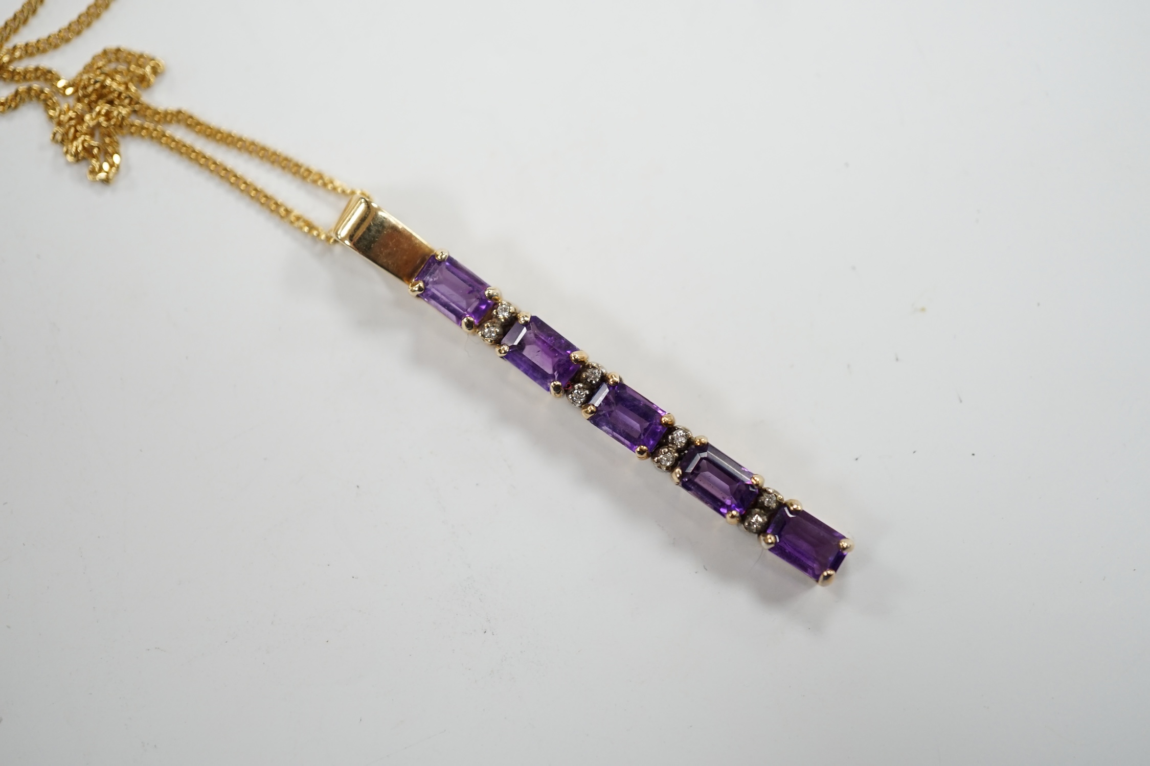 A modern yellow metal, amethyst and diamond chip set line pendant, 47mm, on an 18ct gold fine link chain, 38cm, gross weight 6.4 grams. Fair condition.